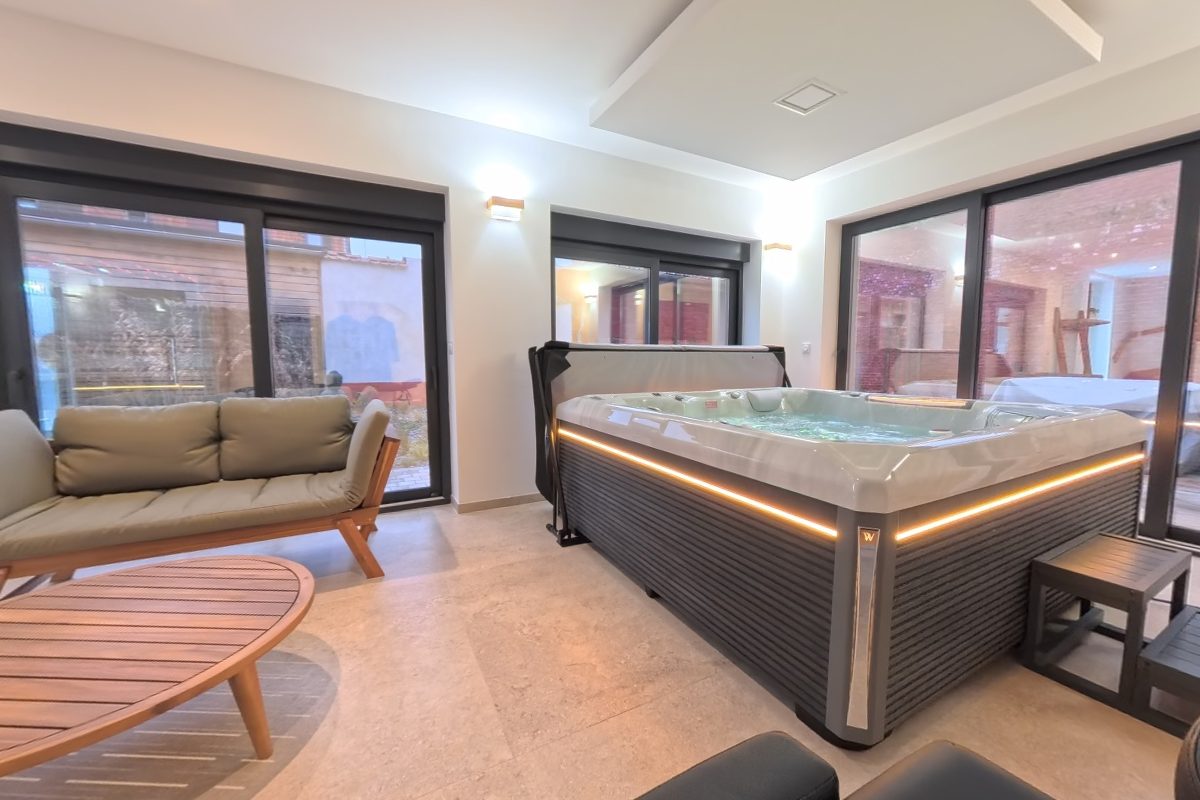 Table de massage au premier plan, jacuzzi et salon en arrière-plan