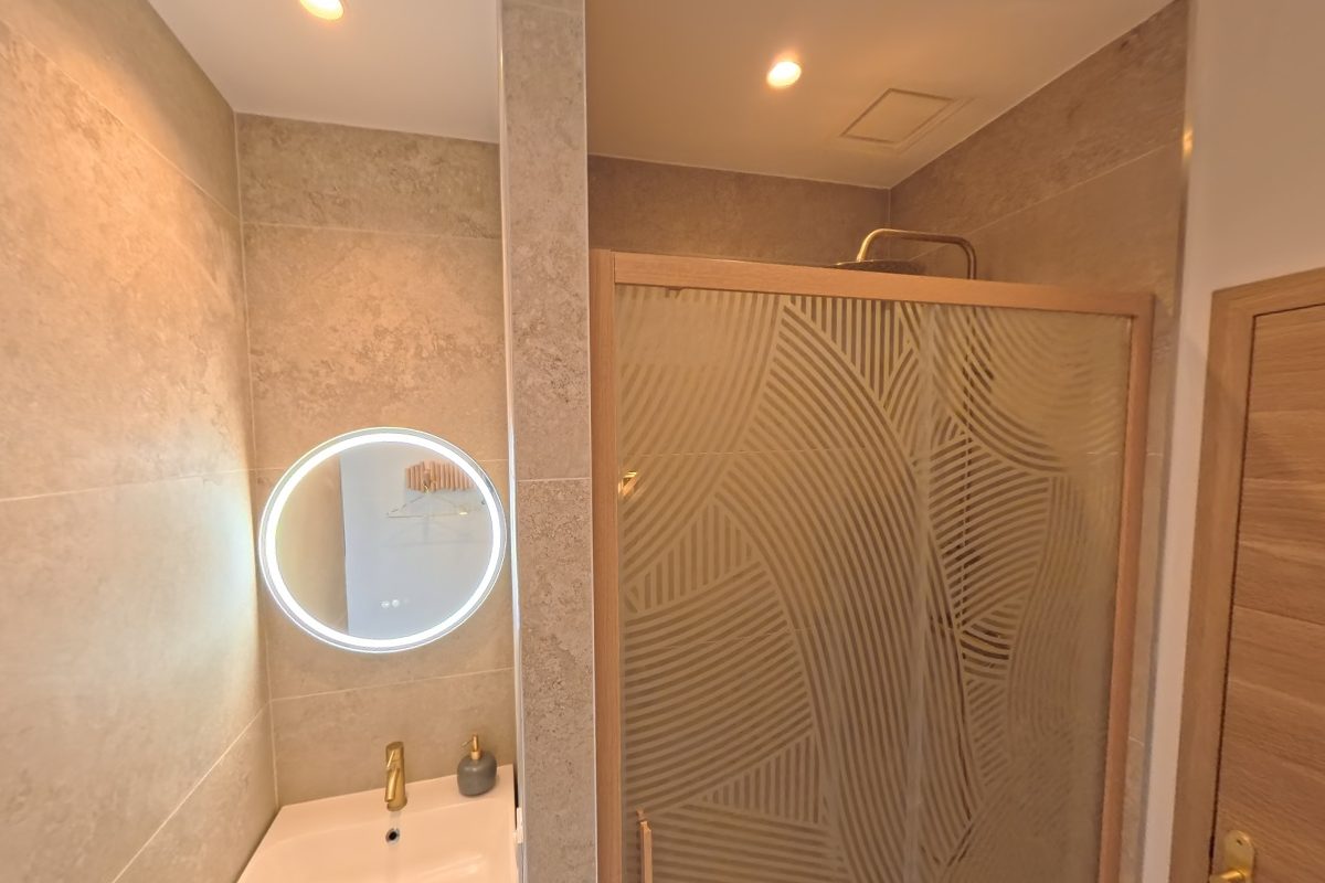 Salle de bain du rez-de-chaussée avec douche vitrée et miroir rond