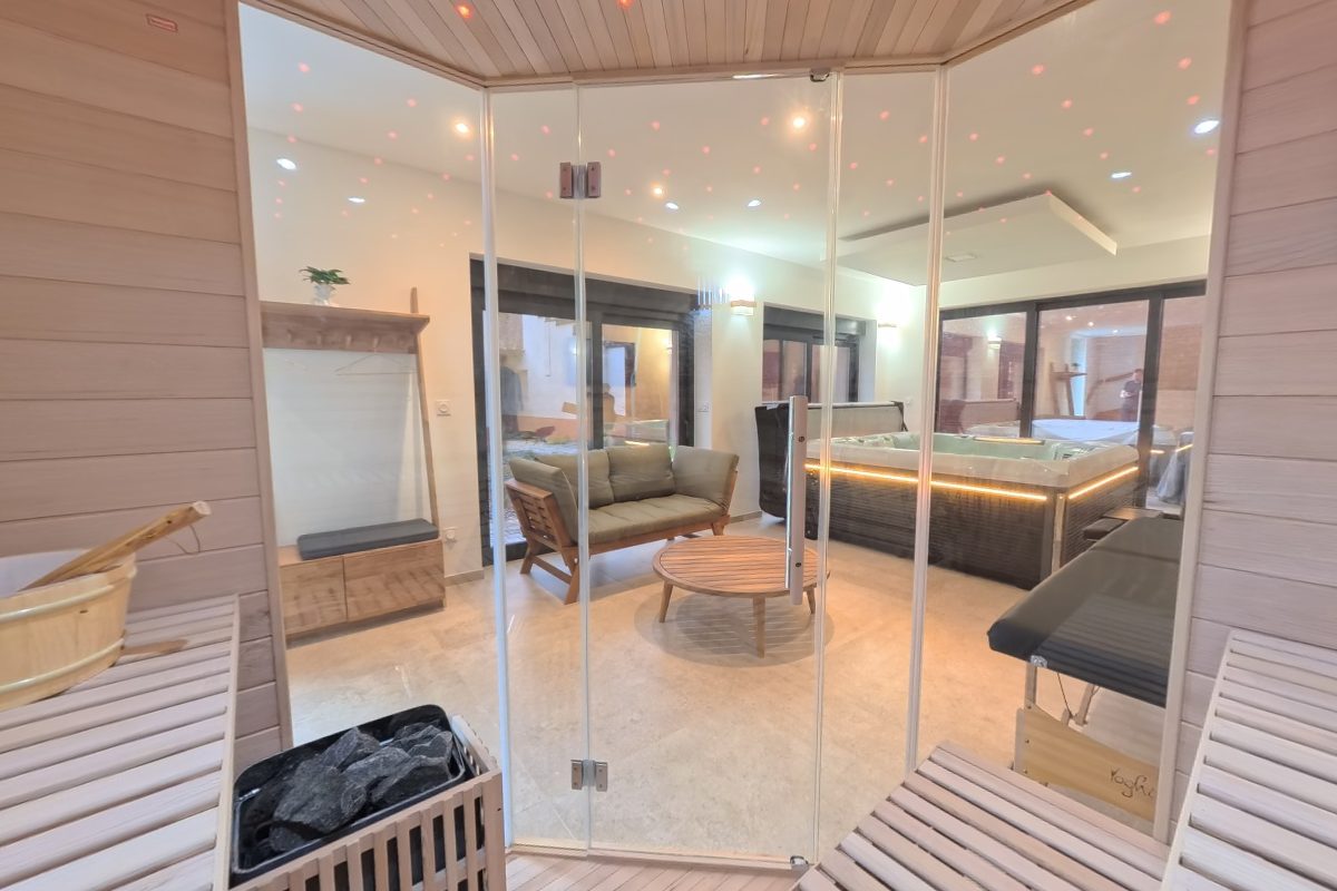 Intérieur du sauna en bois clair avec ciel étoilé et vue sur le salon