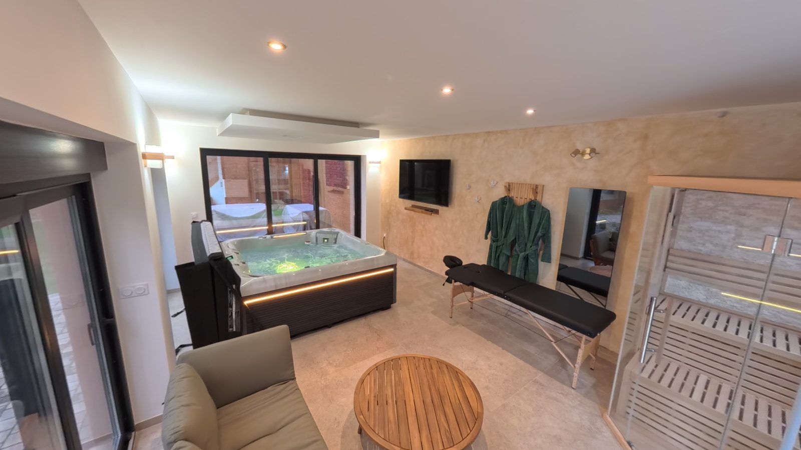 Vue d'ensemble du spa privatif Entre Parenthèses : salon, jacuzzi, table de massage et sauna